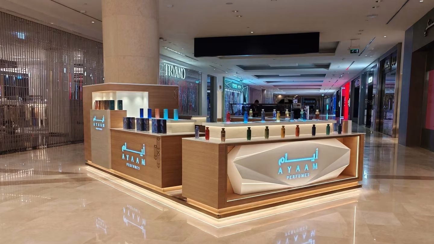 Custom perfume retail kiosk with backlit logo and Corian display counters in a Dubai mall